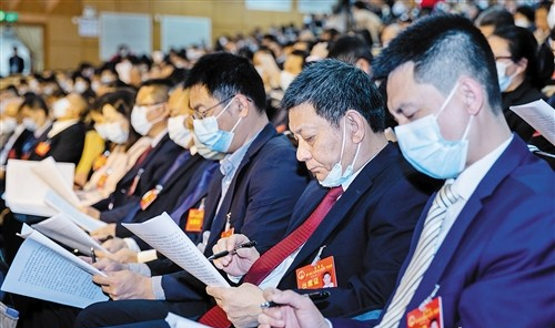 與會代表認真聆聽政府工作報告並做筆記